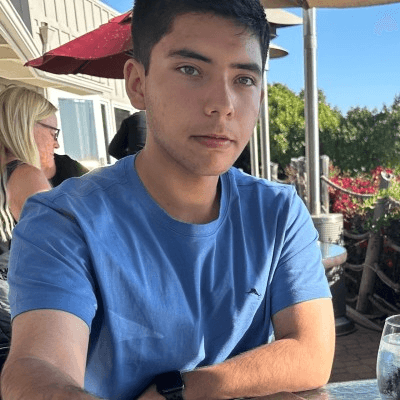 Portrait of William Menjivar seated outdoors in a blue shirt